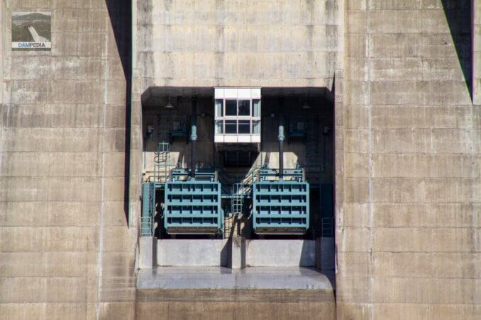 下流の橋より水位維持用放流設備とその見学室を見る
